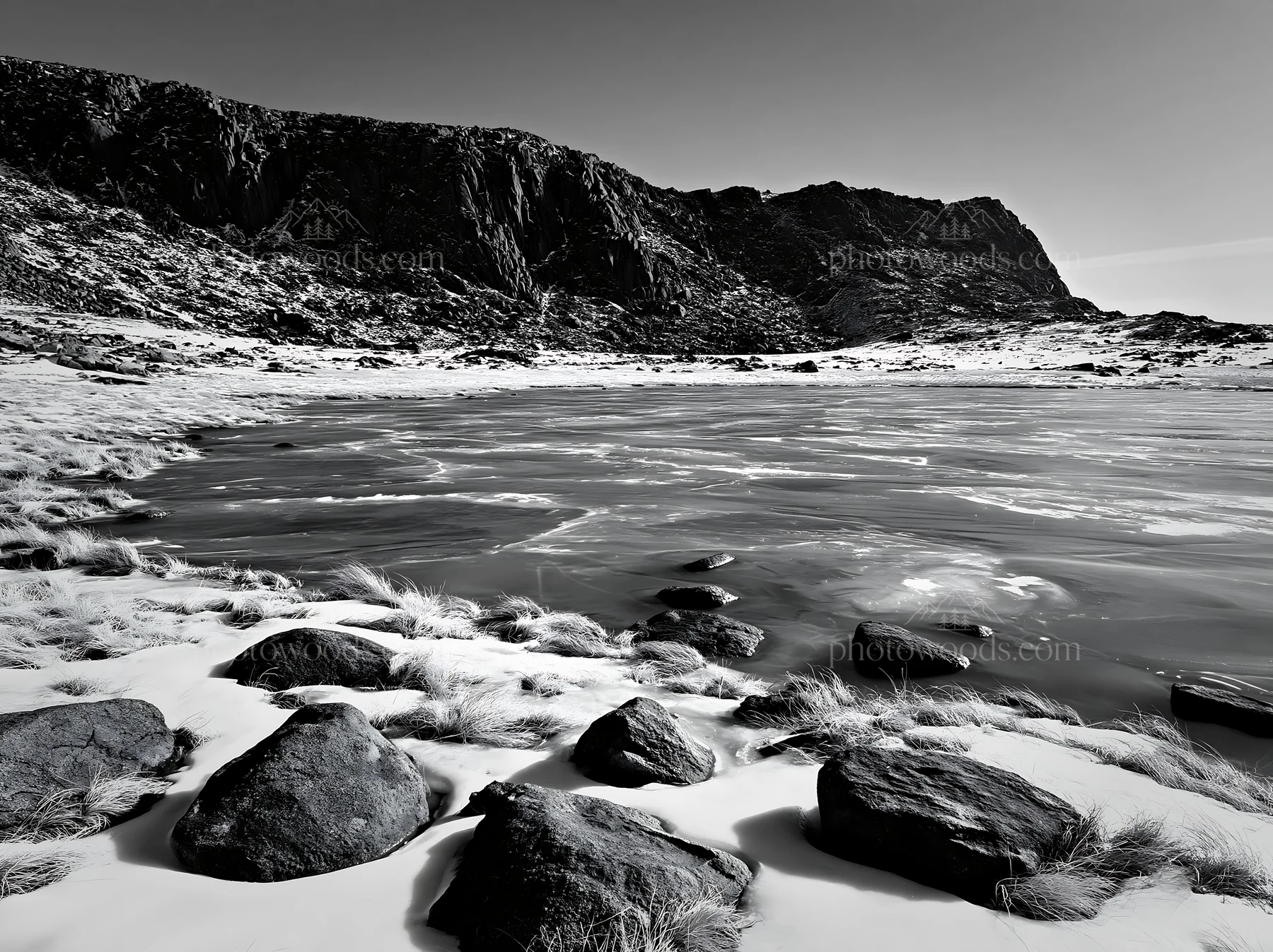 Frozen tarn meadow with rocks in black and white - AI-generated stock image