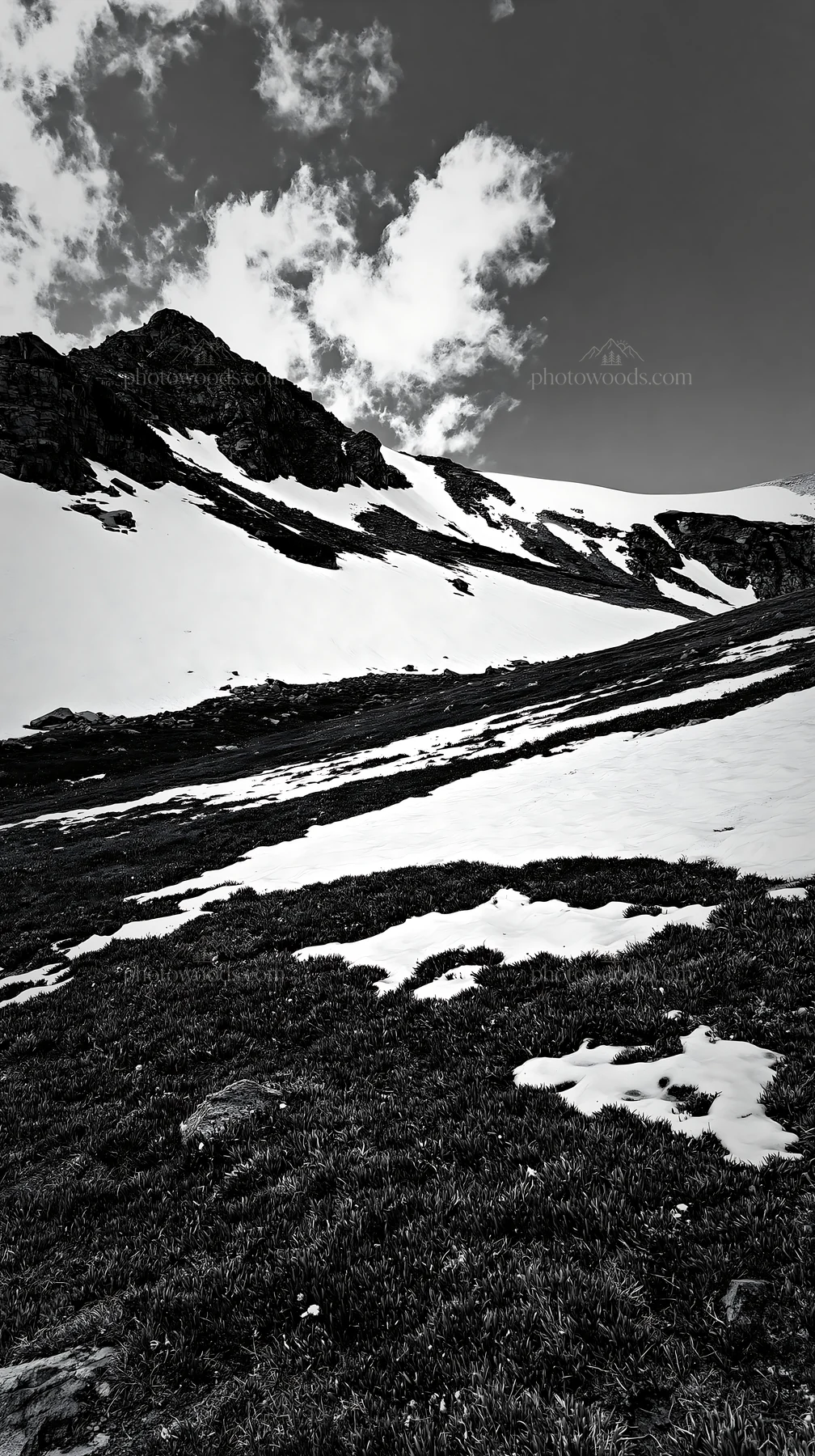 Mountain pass meadow with snow and rocky slopes - AI-generated stock image