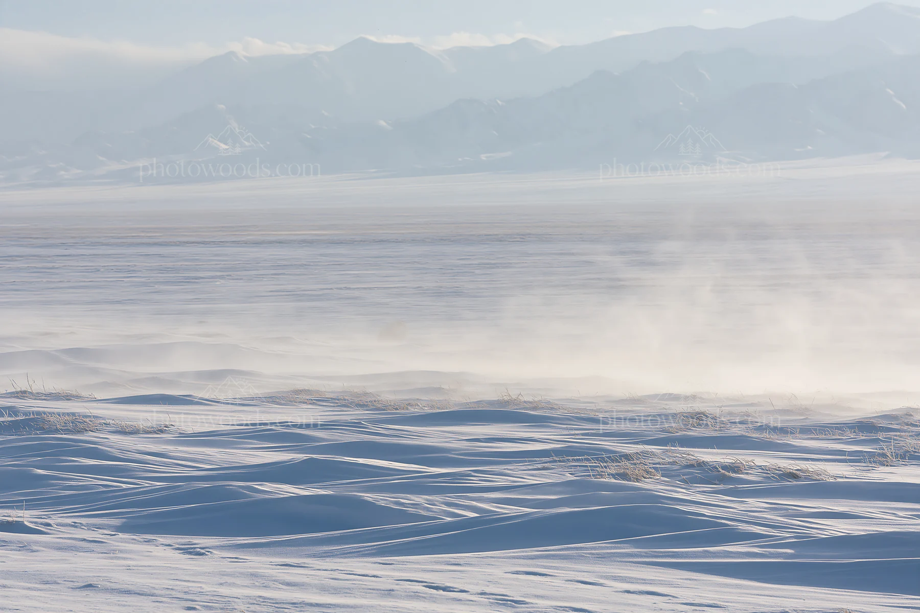 Snowy highland meadow with distant mountains under cloudy sky - AI-generated stock image