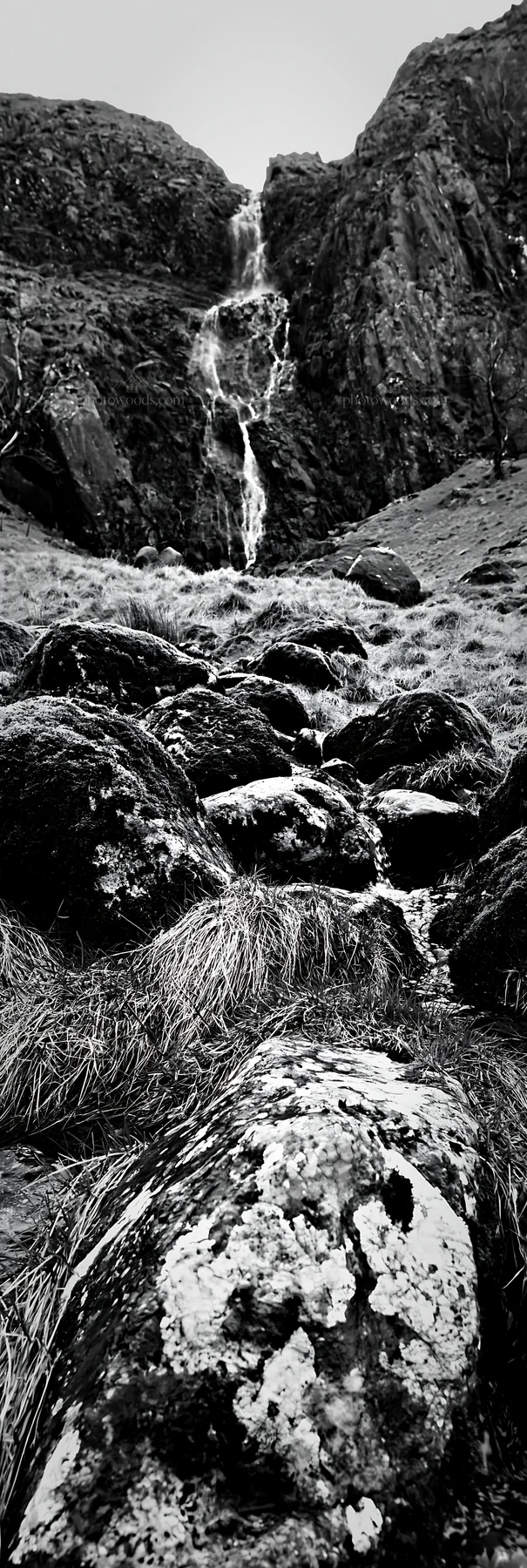 Mossy boulders and waterfall in a meadow landscape - AI-generated stock image