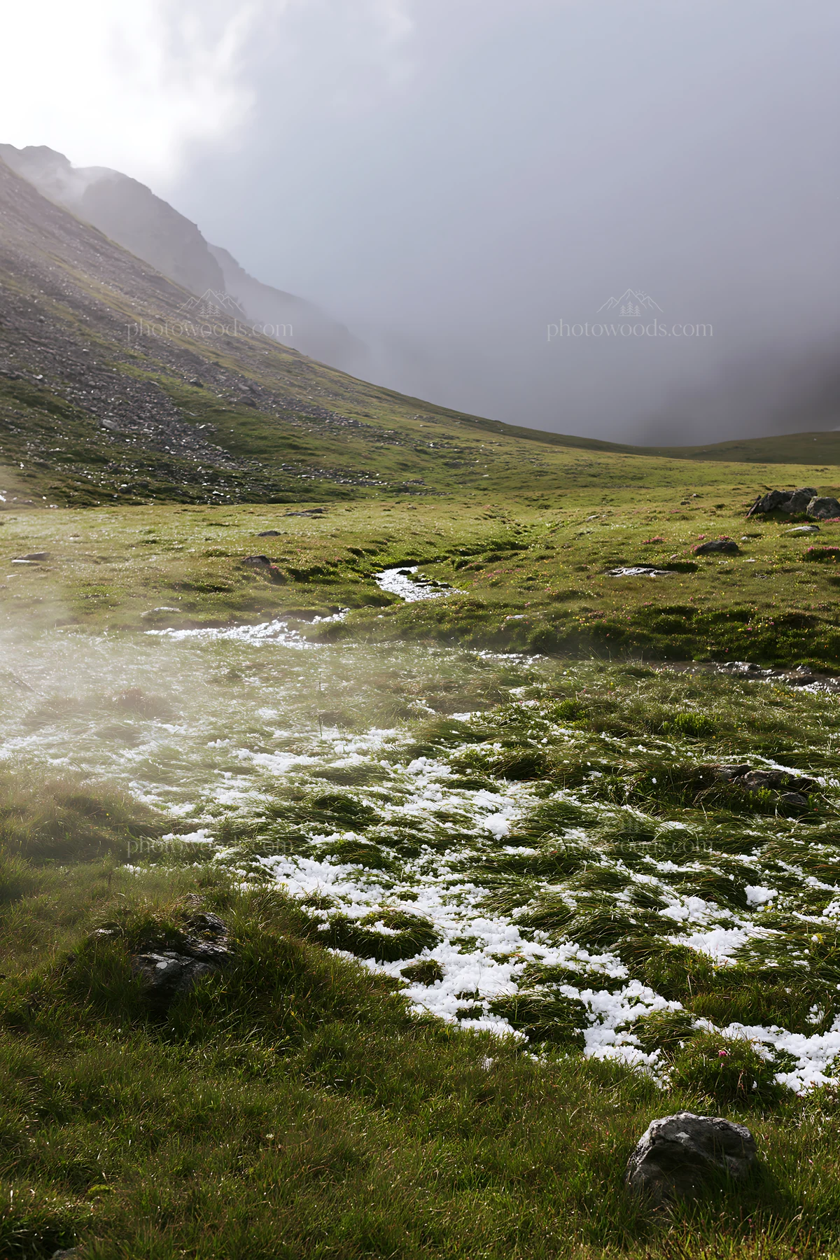Mountain pass meadow with snow and grass in a cloudy setting - AI-generated stock image