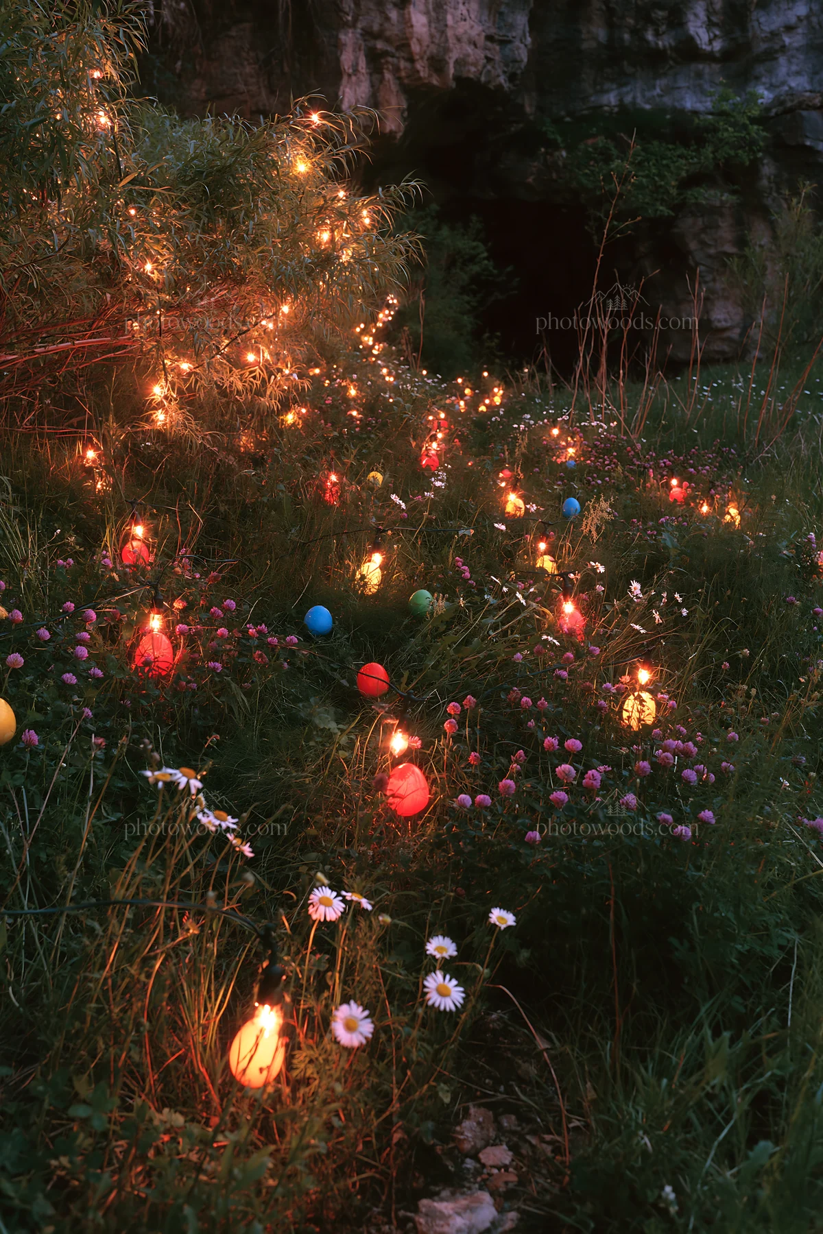 Christmas lanterns at dusk in meadow by cave - AI-generated stock image