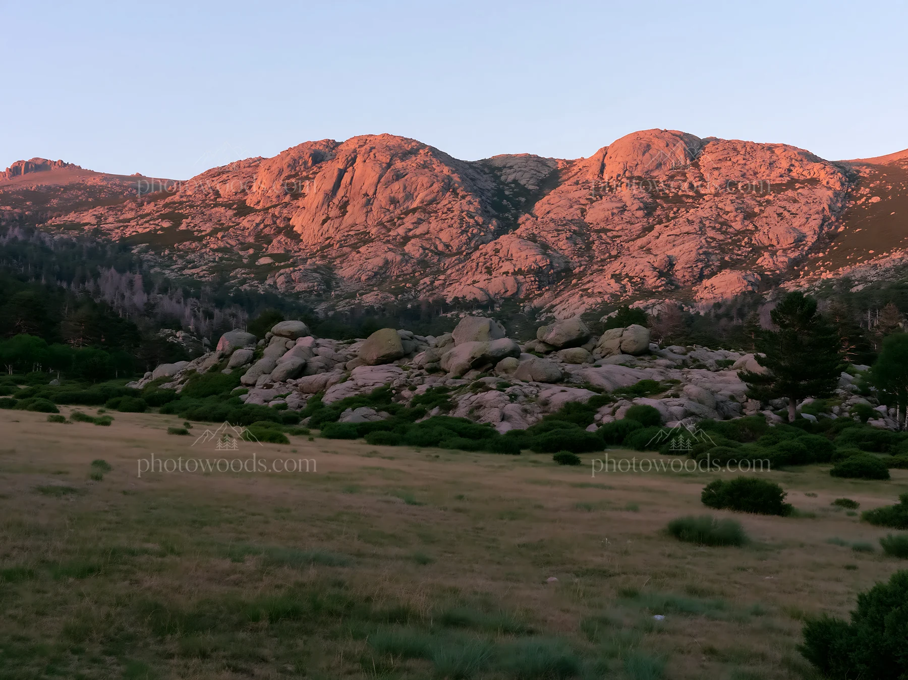 Meadow beneath crags at sunset - AI-generated stock image