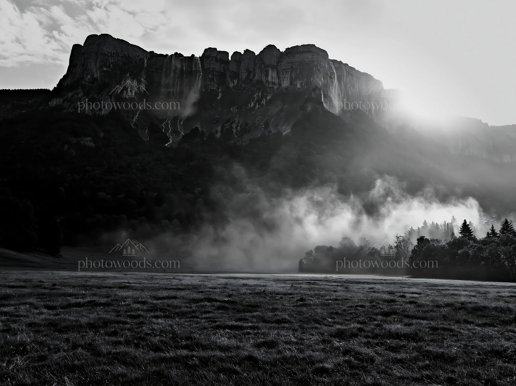 Meadow beneath crags with sunlight and mist - AI-generated stock image