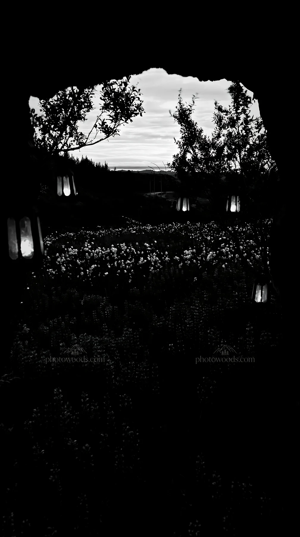 Christmas lanterns in meadow near cave at dusk - AI-generated stock image
