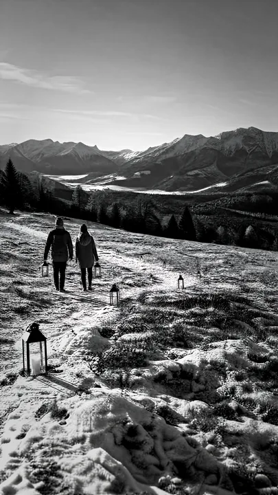 Walking on a snowy path in a Christmas meadow with lanterns - AI-generated stock image