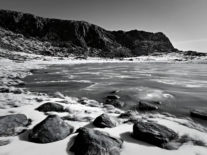 Frozen tarn meadow with rocks in black and white - AI-generated stock image