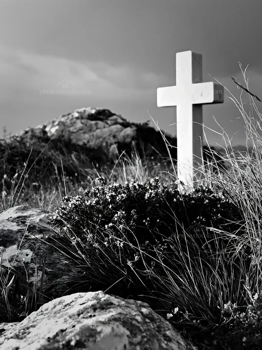 White Christian cross in remote meadow with rocks and grass - AI-generated stock image