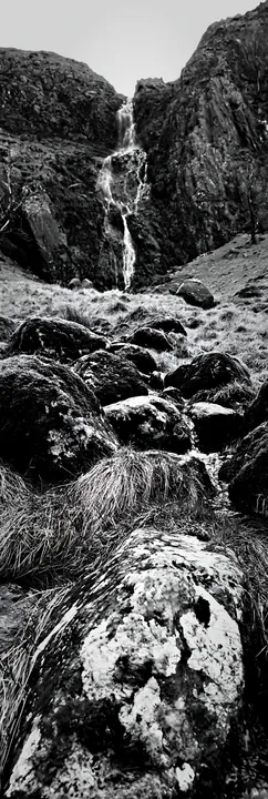 Mossy boulders and waterfall in a meadow landscape - AI-generated stock image