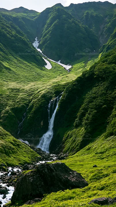 Snowmelt waterfall in Toyama alpine meadow with rocky foreground - AI-generated stock image