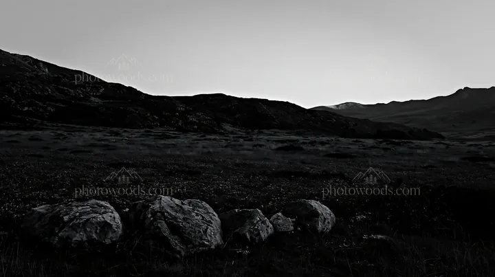 Meadow with boulders and mountains at dusk - AI-generated stock image