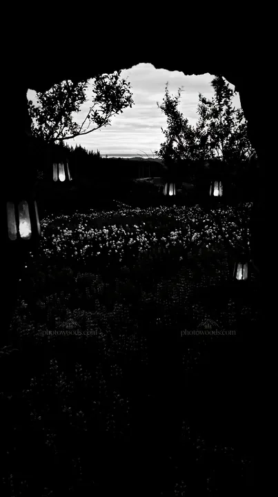 Christmas lanterns in meadow near cave at dusk - AI-generated stock image