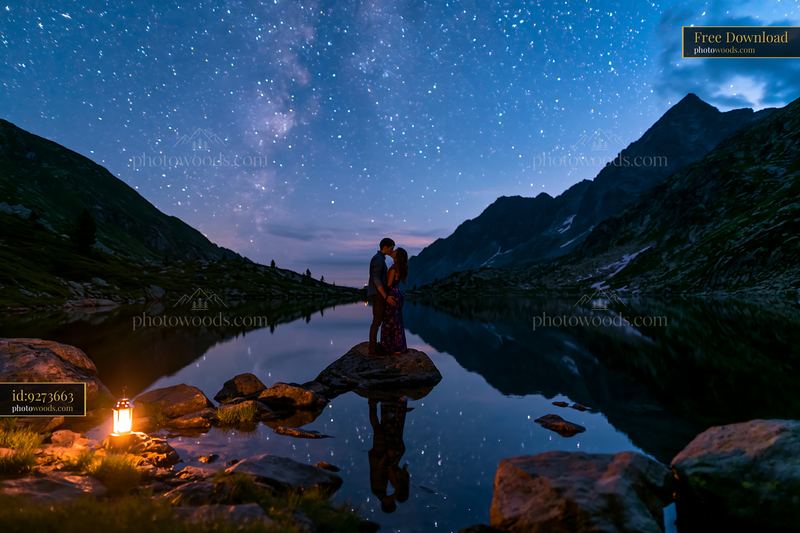 Couple kisses under stars beside a lake at night