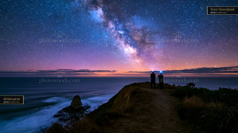 Couple photographing Milky Way above the ocean at night