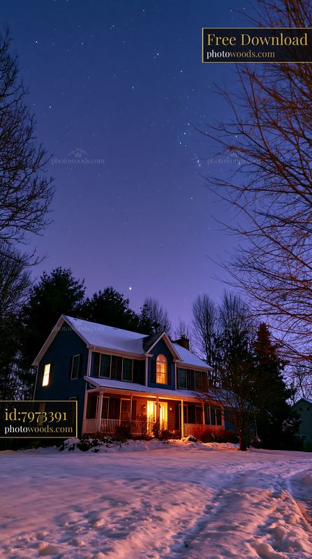 Snowy house with warm light under a starry night sky