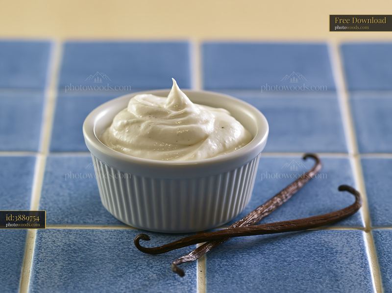 Cream dose with vanilla pods in a white dish on blue tiles