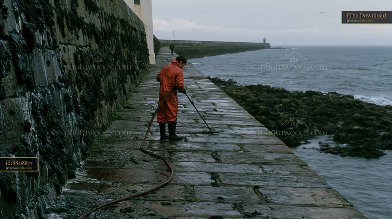 Lighthouse maintenance worker cleans the path near the water