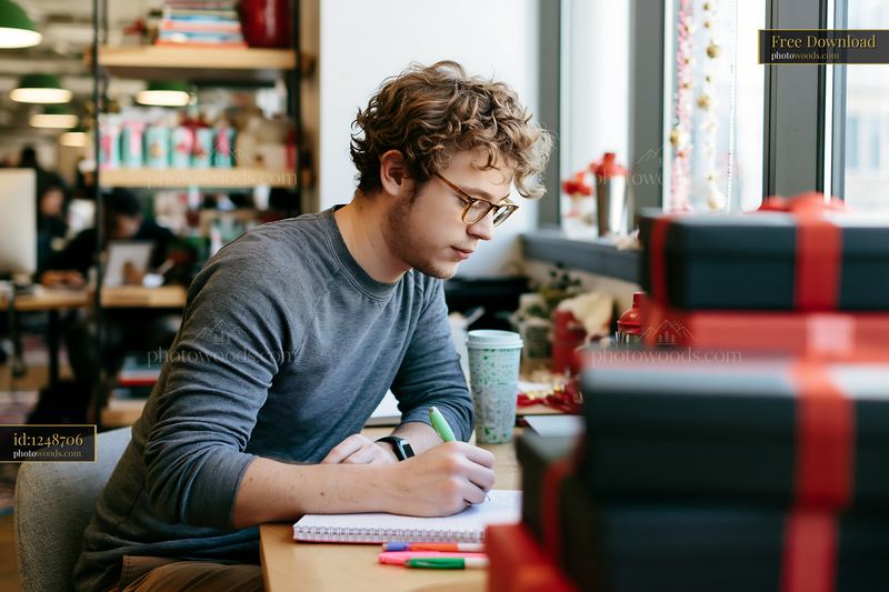 Person writing gift list at desk in modern office setting