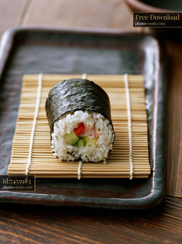 Single sushi roll on bamboo mat resting on a dark plate
