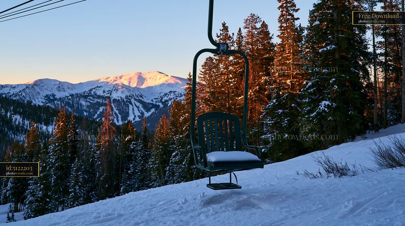 Golden sunlight on snowy peaks and a ski lift in winter landscape