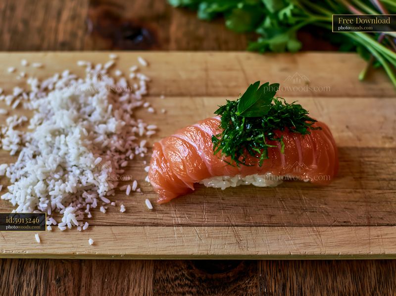 Sushi piece with fresh herb garnish and rice on wooden board