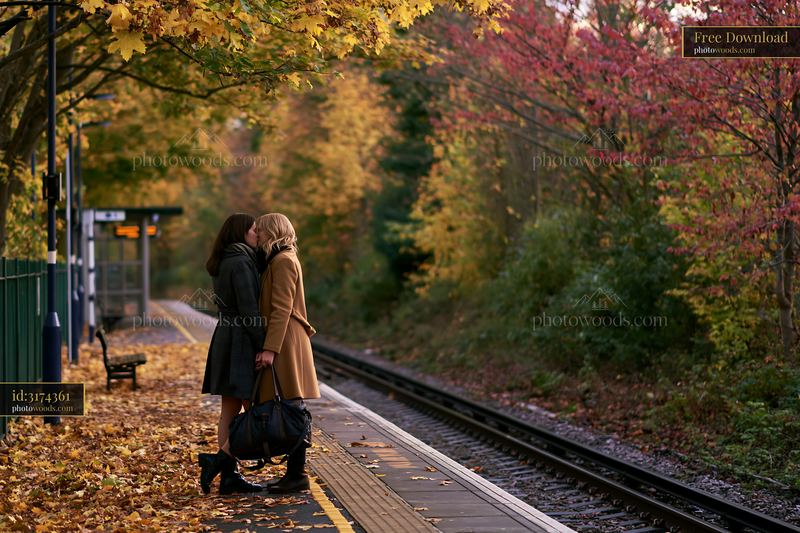 Partners kissing on train platform in autumn foliage