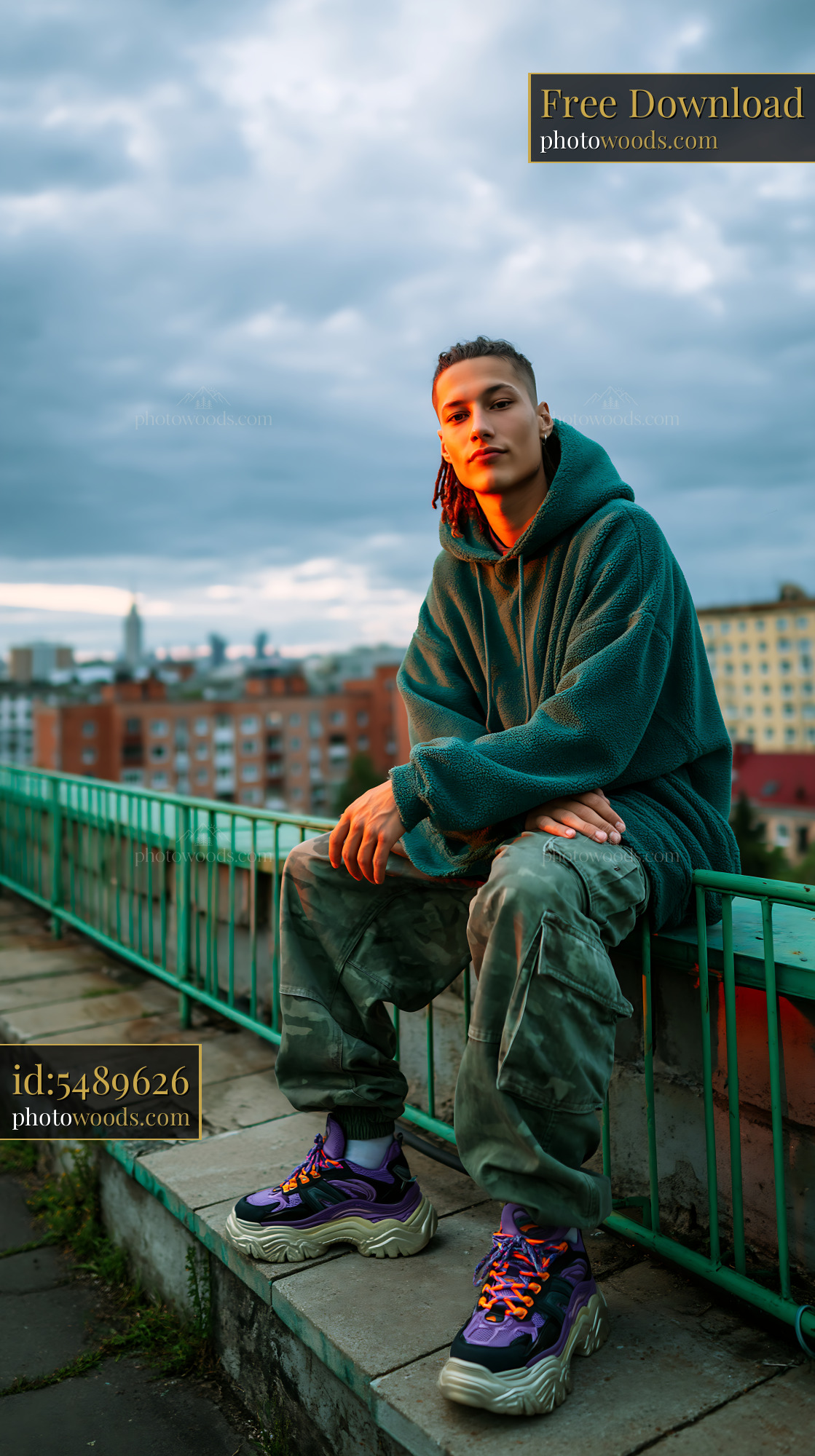 Young Man in Oversized Hoodie Sitting on Urban Wall at Sunset