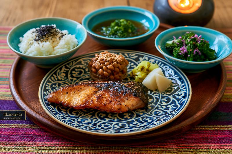 A breakfast plate with Japanese breakfast includes grilled salmon, rice, natto, pickles, and side dishes.