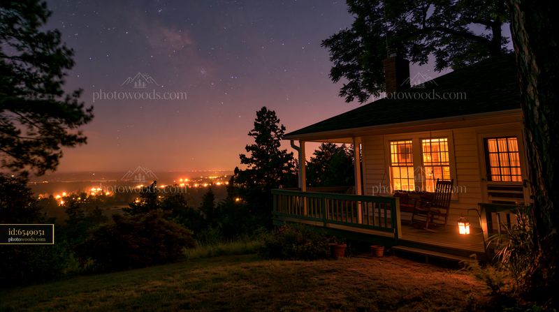House with porch swing under starry sky near city lights