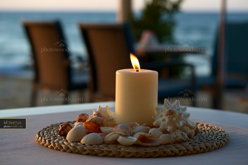 Candle surrounded by seashells on a table by the beach