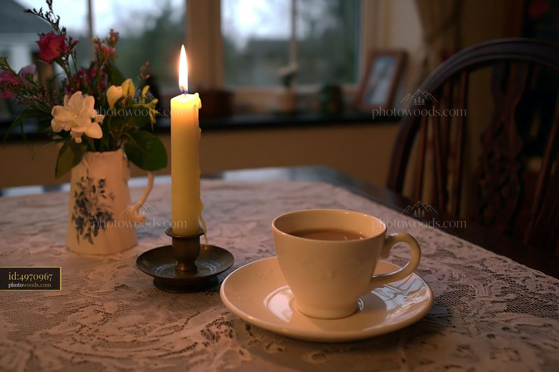 Candle with cup on a table in cozy indoor setting