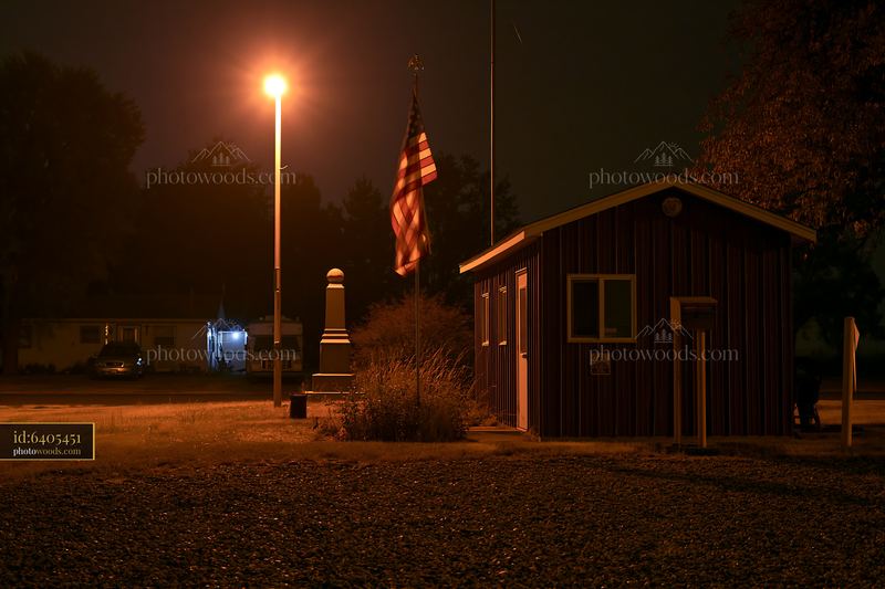 Cemetery monument and US flag illuminated at night