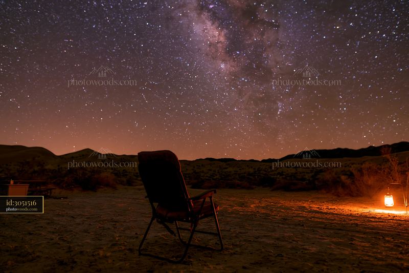 Starry night above a desert campsite with a chair and lantern