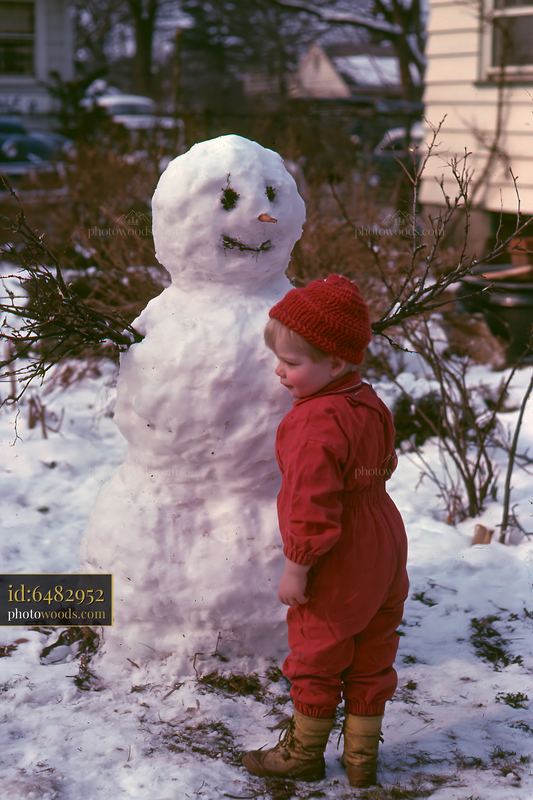 Child playing near a snowman in a snowy backyard