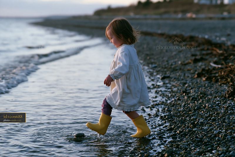 Child walking on pebbly coastline beach during sunset
