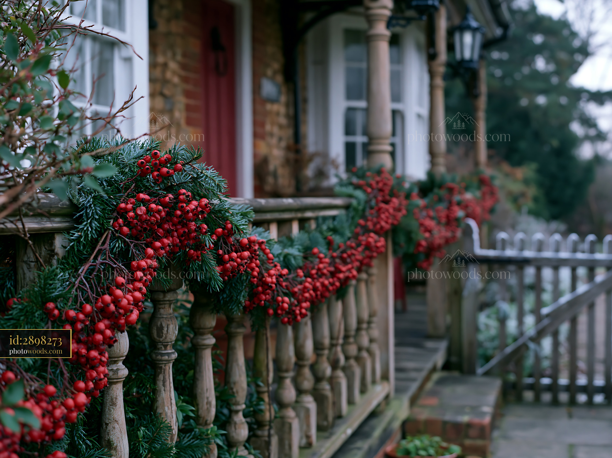 A country cottage with Christmas decorations has a porch draped in garlands.