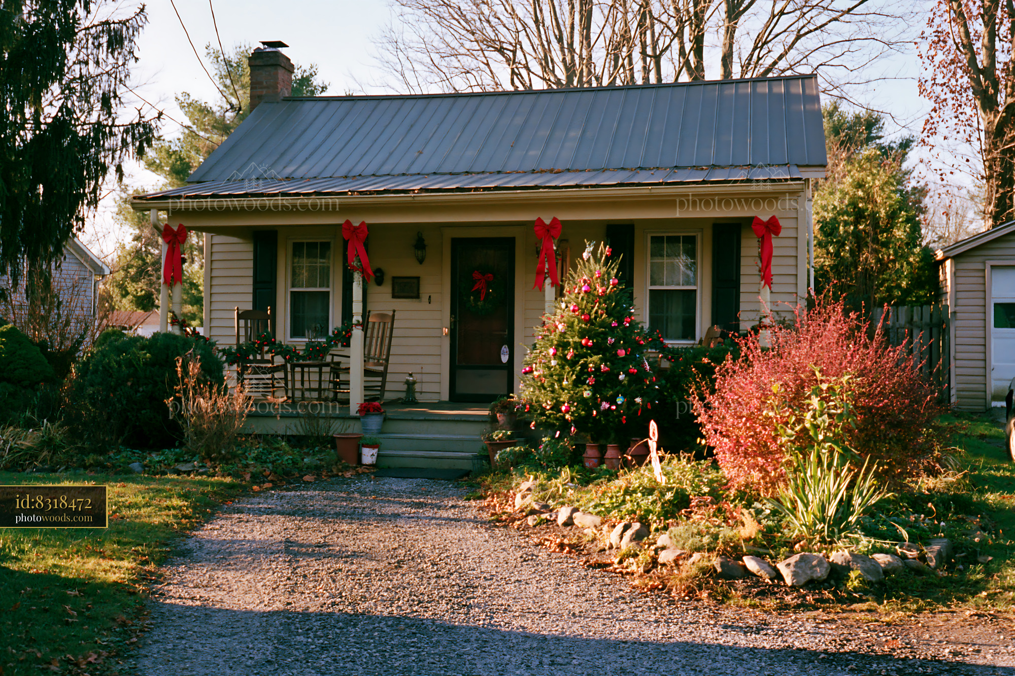 A country cottage with Christmas decorations stands surrounded by greenery.