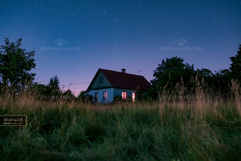 Country home under clear night sky with bright windows