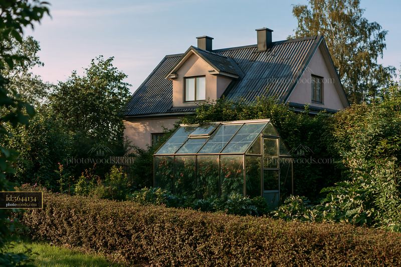 Country house surrounded by hedges with a greenhouse nearby