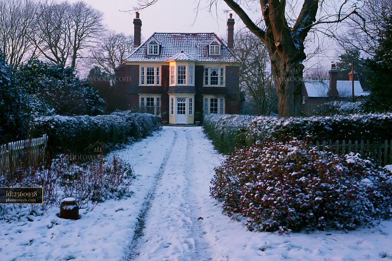 Country house surrounded by hedges with snowy pathway