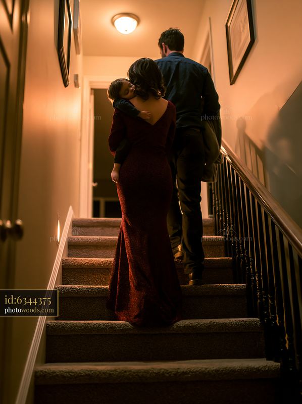 Parents carrying sleeping child up the stairs at night
