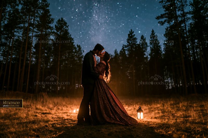 Couple kissing under stars in a forest clearing