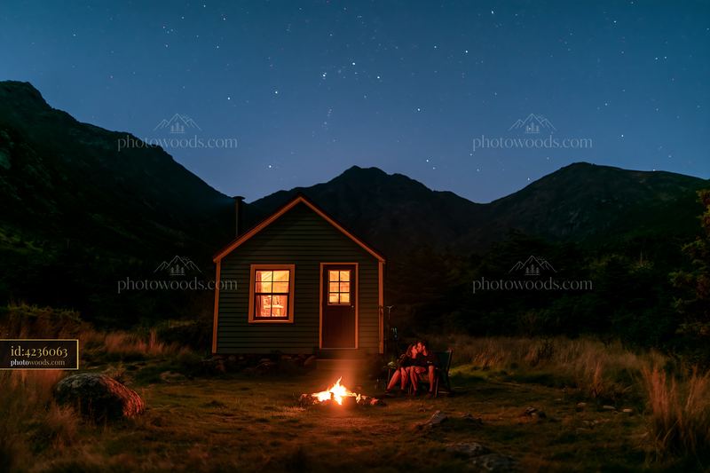Couple kissing beside a campfire under stars at a cabin