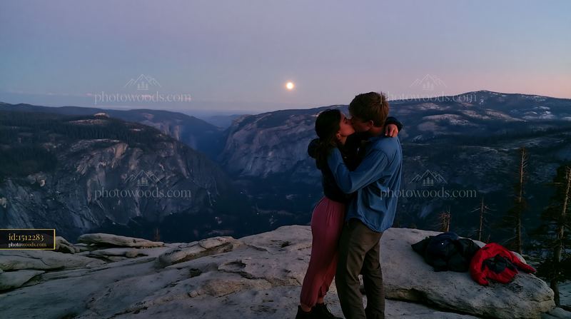 Lovers kissing on a mountain overlook at night under the moon