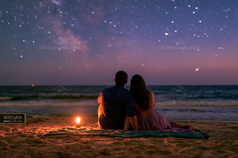Starry night above a sandy beach with a couple enjoying the view