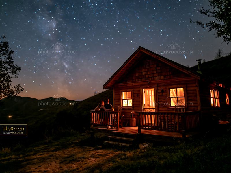 Couple beside a mountain cabin under stars at night