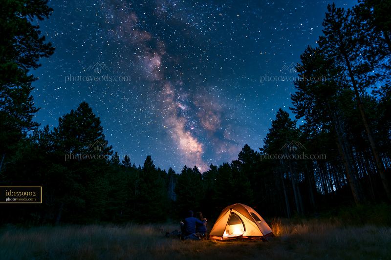Couple viewing the Milky Way from a forest clearing at night