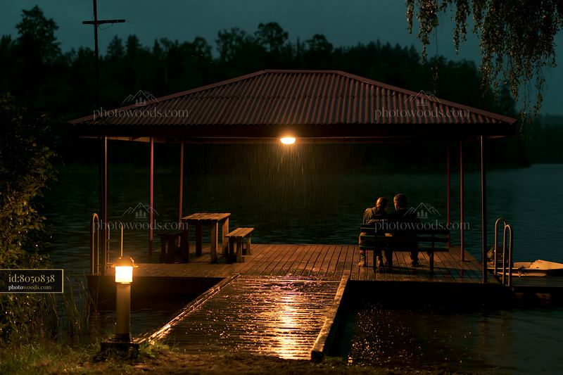 Couple relaxing beside a lake at night with rain falling