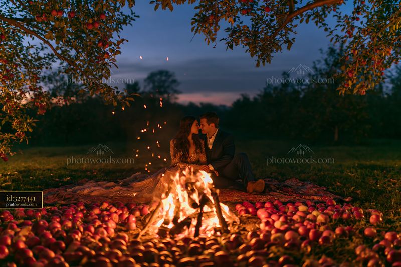 Couple spending time by a fire in a night orchard setting