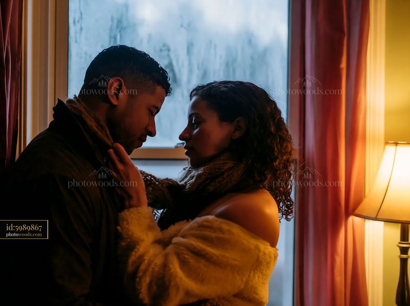 Couple sharing a kiss on forehead indoors near a lamp